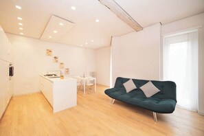 A modern living space with a kitchen, dining area, and a green sofa.