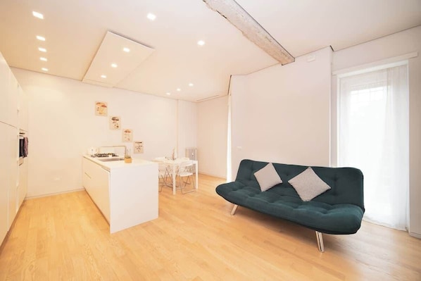 A modern living space with a kitchen, dining area, and a green sofa.