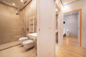 A modern bathroom with a glass shower enclosure, a white sink, and a toilet.