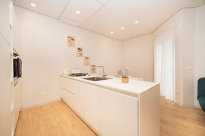 A modern kitchen with white cabinetry, a built-in sink, and a small countertop.