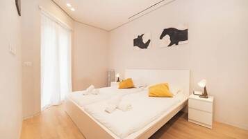 Ein modernes Schlafzimmer mit Bett, Nachttischen und Kunstwerken an der Wand.