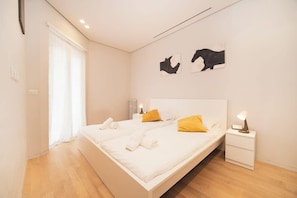 A modern bedroom with a bed, bedside tables, and artwork on the wall.