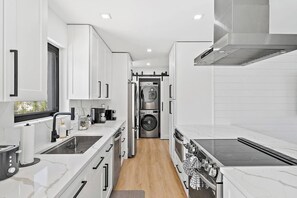 A compact kitchen with white cabinetry, a built-in oven, a microwave, and a washing machine.