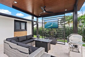 Un espace extérieur aménagé, abrité, avec un canapé, une table et un barbecue.