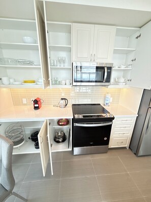 Una cocina moderna con armarios blancos, un microondas de acero inoxidable, una estufa a gas y un horno empotrado.