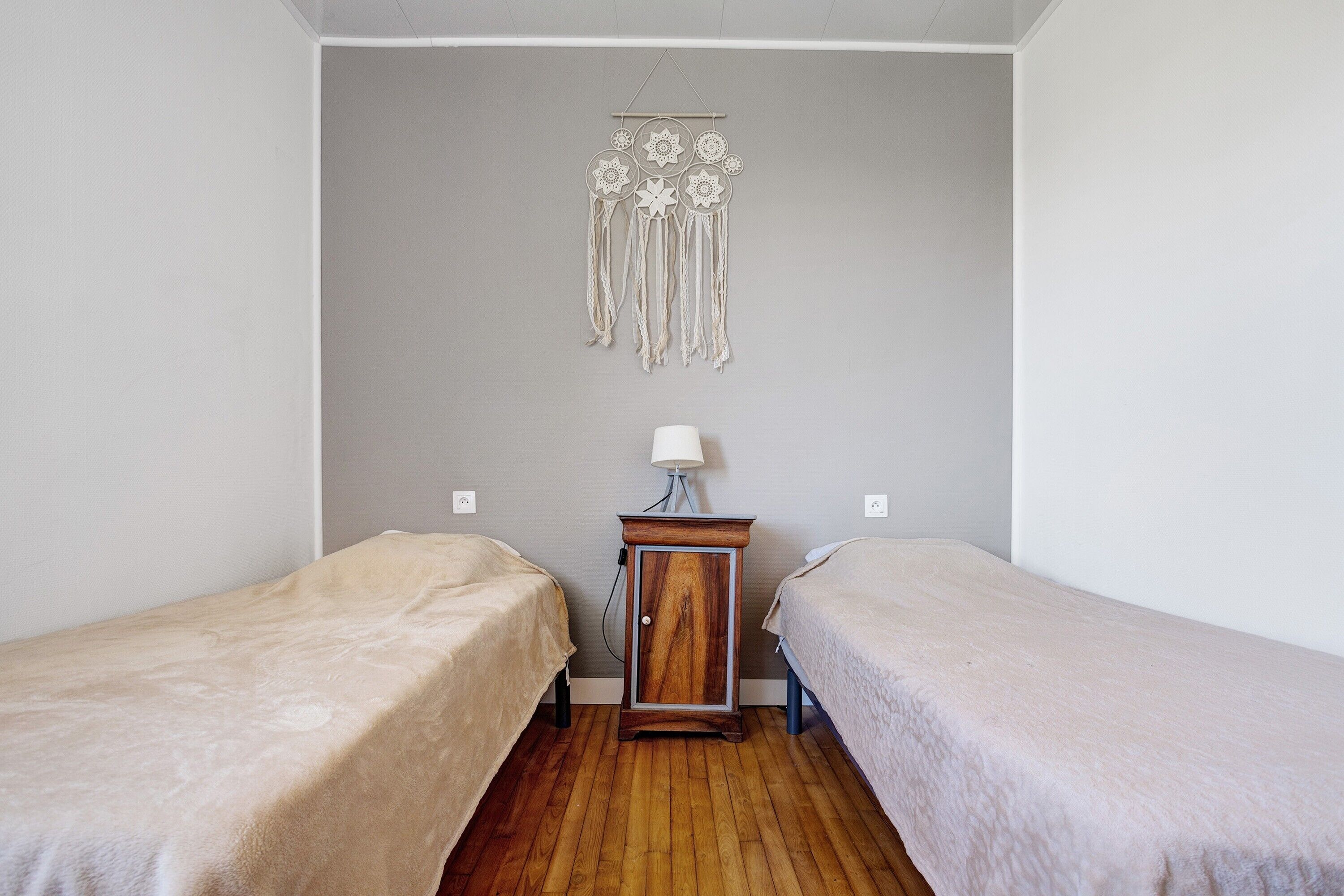Una stanza con due letti, un comodino con una lampada e un quadro appeso al muro.