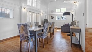 A dining area with a wooden table and chairs, a television, and a clock on the wall.
