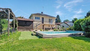 A house with a swimming pool, a wooden deck, and a garden.