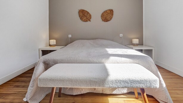 A bedroom with a bed, two bedside tables, and a wall art piece.