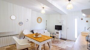Eine moderne Küche mit weißen Schränken, einem Holztisch und einem Fernseher.