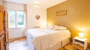 Ein Schlafzimmer mit Bett, Nachttisch und einem Fenster mit Vorhängen.