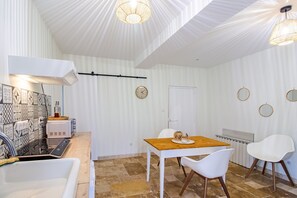 Eine moderne Küche mit weißer Arbeitsplatte, einem Einbauofen und einem Essbereich mit Holztisch und weißen Stühlen.