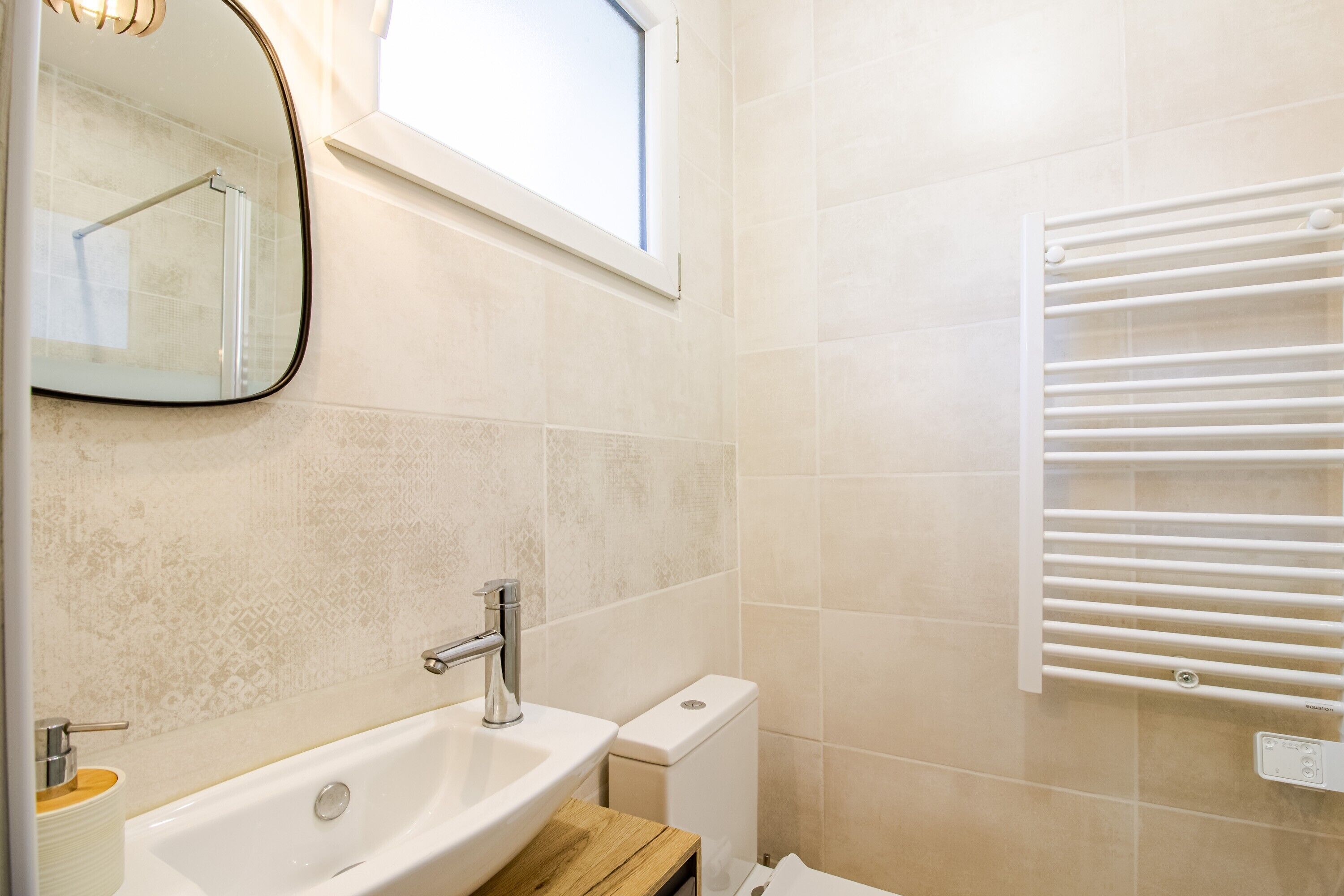 A bathroom with a sink, mirror, window, and towel rack.