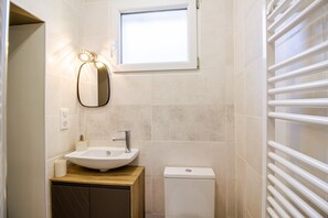 Ein Badezimmer mit Waschbecken, Spiegel, Toilette und Fenster.