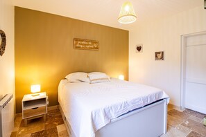 Ein Schlafzimmer mit Bett, Nachttisch, Lampe, Wanddekoration und einer Tür.