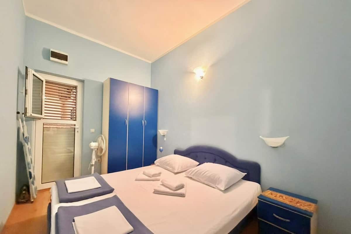 A bedroom with a bed, two bedside tables, a wardrobe, a bedside lamp, and a wall-mounted light.