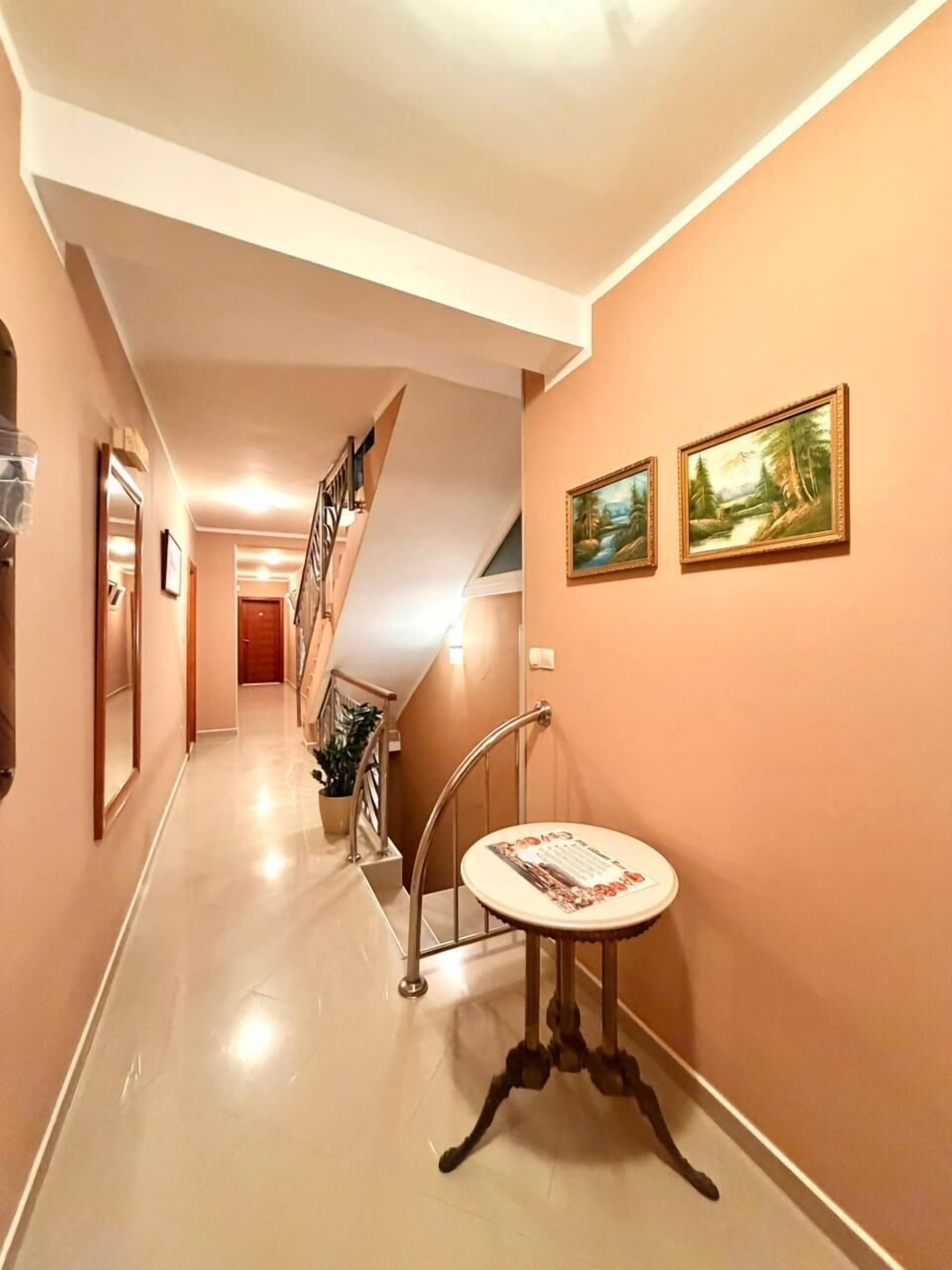 A hallway with a staircase, a small table with a placemat, and two framed paintings on the wall.