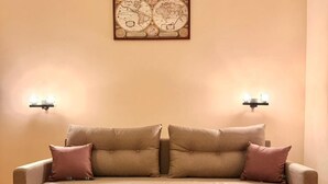 Ein Wohnzimmer mit einem beigefarbenen Sofa, zwei passenden Kissen, einem Holztisch und einer Weltkarte als Wandbild.