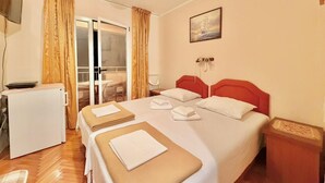 Ein Hotelzimmer mit Bett, Schreibtisch, Stuhl und einem Fenster mit Vorhängen.