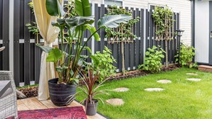 Une terrasse agrémentée de plantes en pot, d’une chaise en osier et d’une plateforme en bois.