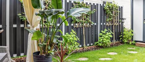 A patio with potted plants, a wicker chair, and a wooden deck.