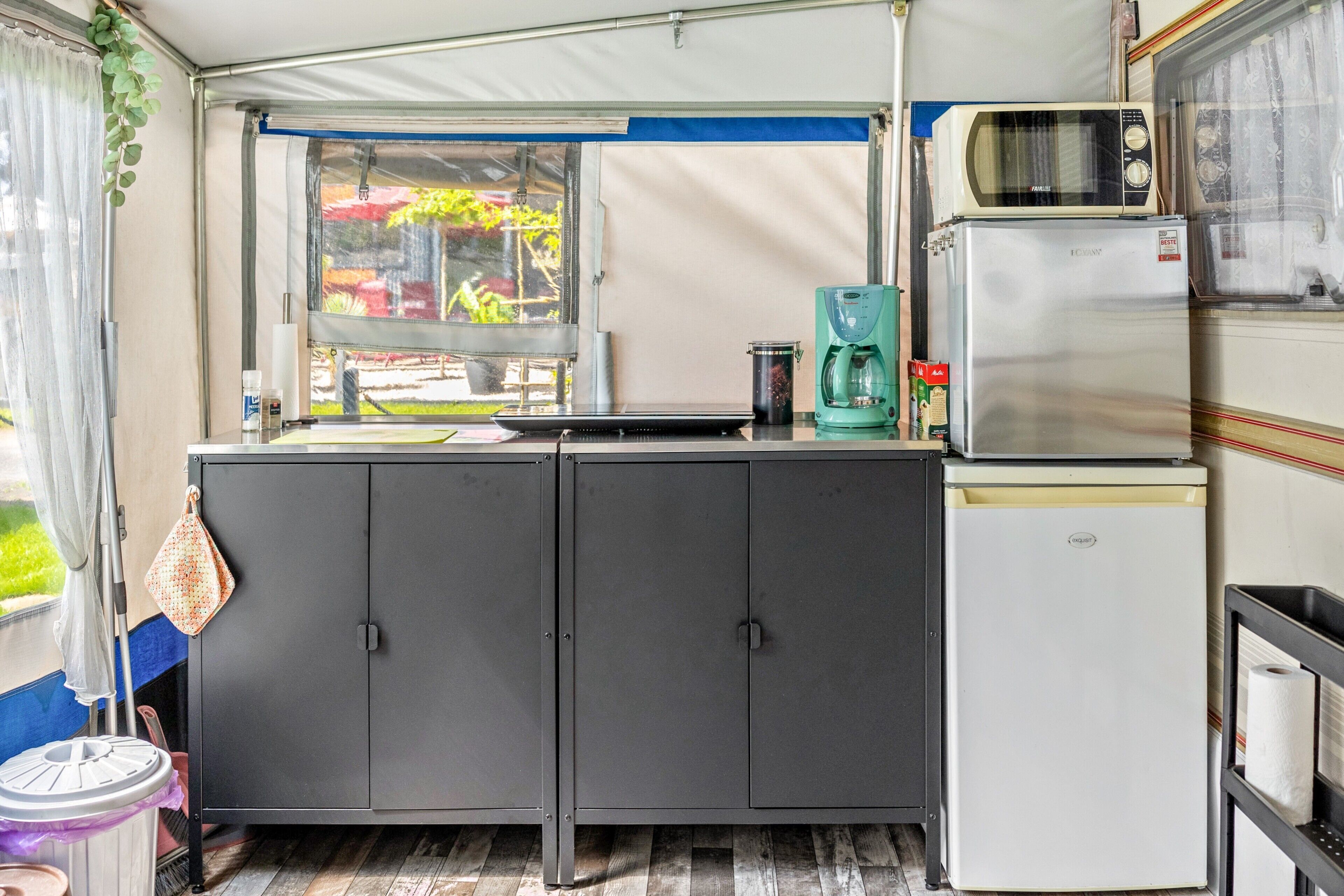 A compact kitchen with a window, a microwave, a refrigerator, and a coffee maker.