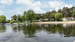 Une vue sur le lac, avec des bateaux amarrés, des arbres et des maisons le long de la rive.