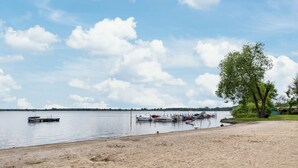 Une vue sur le lac, avec des bateaux amarrés, une plage de sable et un arbre.