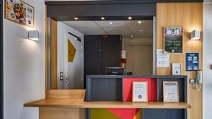 Un mostrador de recepción con encimera de madera, un panel negro y rojo, y certificados enmarcados.