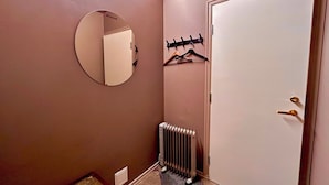 Un couloir avec un radiateur, un porte-manteau et une porte.