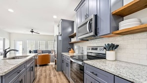 Una cocina moderna con encimeras de granito, electrodomésticos de acero inoxidable y piso de madera.