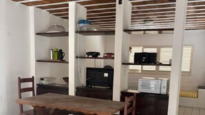 A dining area with a wooden table and benches, a kitchen area with appliances, and a tiled floor.