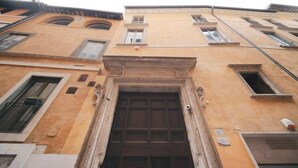 Une façade d’immeuble avec une entrée centrale, de nombreuses fenêtres et une porte bien visible.