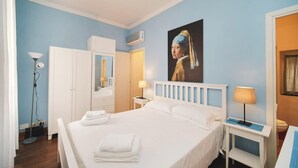 Une chambre d’hôtel avec un grand lit, une armoire, un bureau avec une lampe et un tableau au mur.