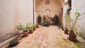 Un couloir en arc, agrémenté de plantes en pot et d’une statue.