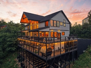 A multi-story waterfront property with a deck, outdoor seating, and a barrel.