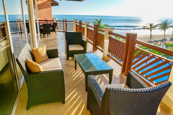 A balcony with wicker furniture, a table, and a view of the ocean. - Stunning Ocean View! (Bajos de Chila)