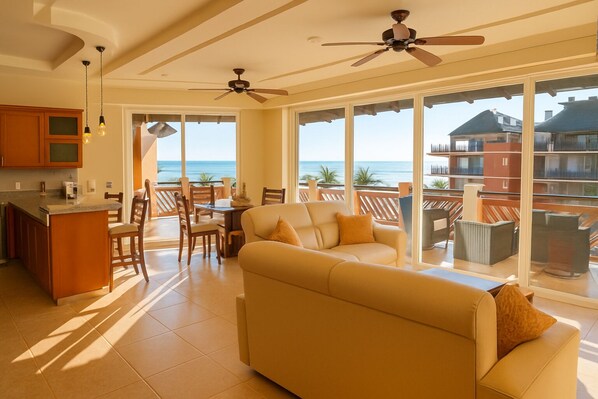 A spacious living area with a sofa and chairs, a dining table, and a kitchen area. Large windows provide a view of the ocean. - Stunning Ocean View! (Bajos de Chila)
