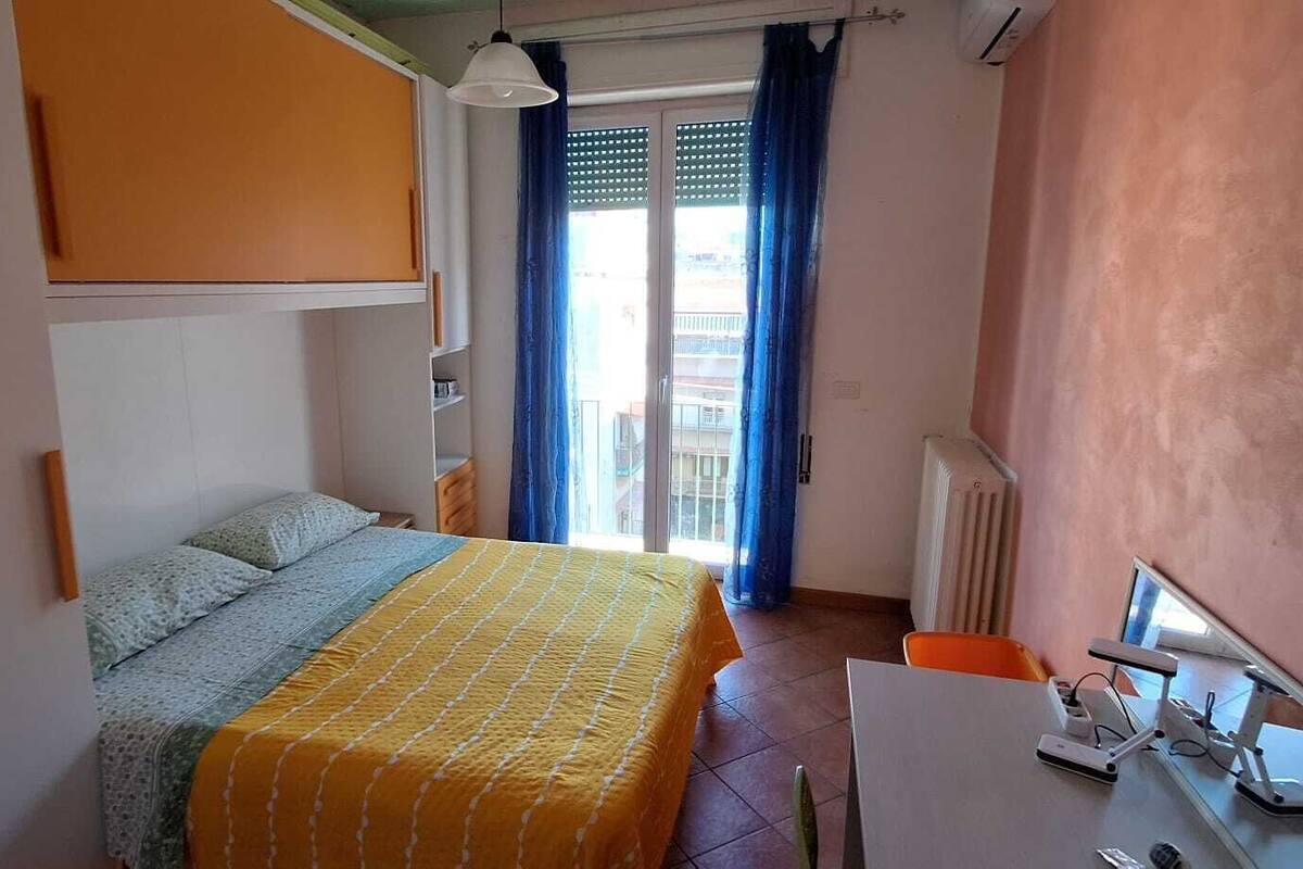 Un dormitorio con cama, escritorio y radiador.