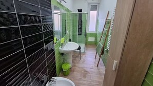A bathroom with a black and green tiled wall, a white sink, and a shower area. - DOMUS BAIANO  (Naples)