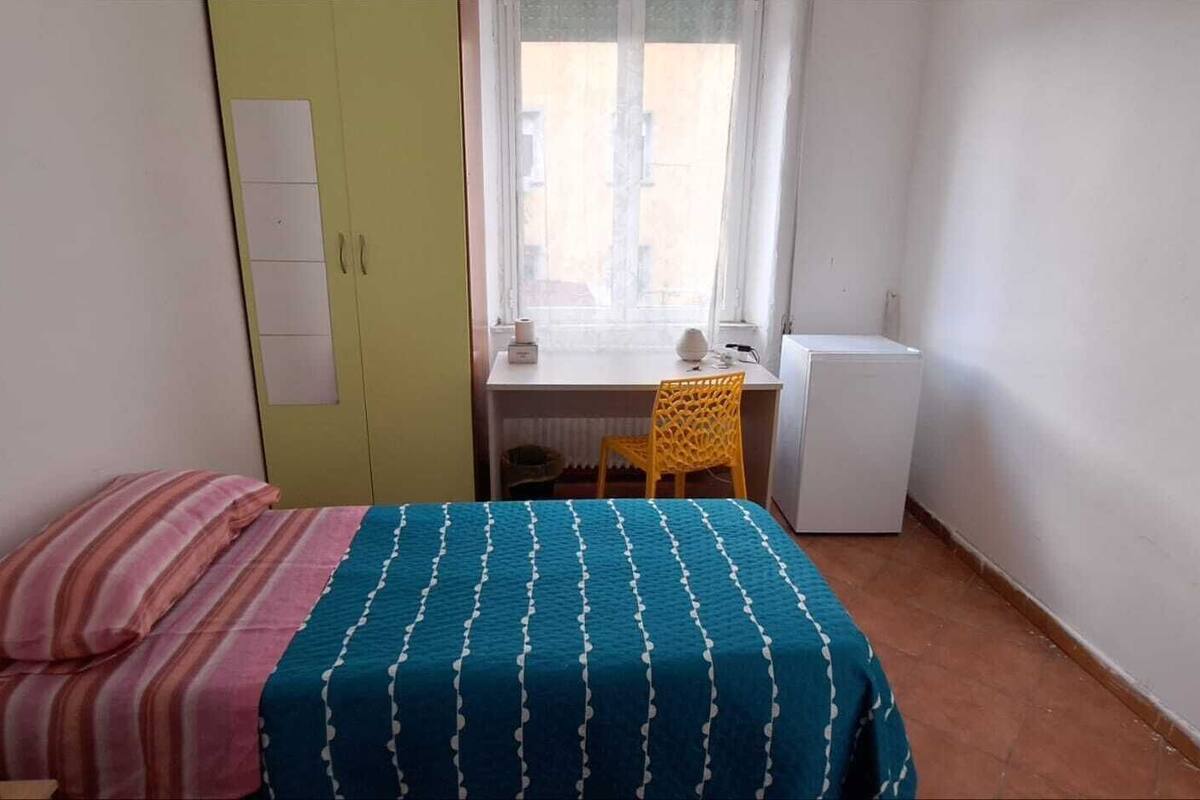 Una habitación pequeña con una cama, un escritorio y una silla.