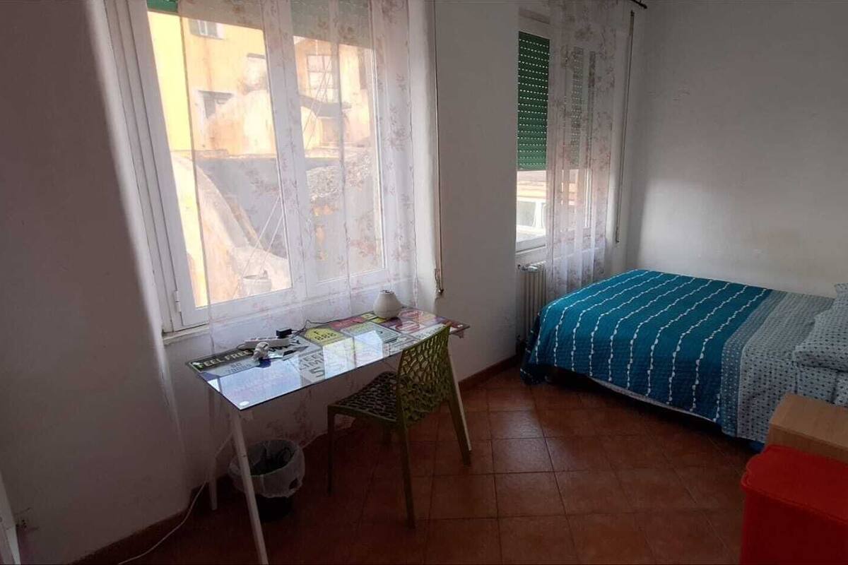 Una habitación pequeña y ordenada con una cama individual, un escritorio y una silla.