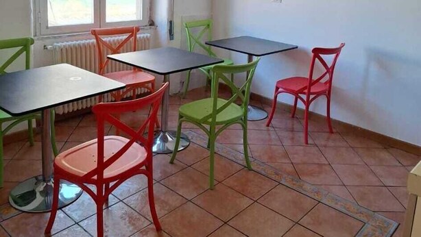 A room with a tiled floor, a window with blinds, a radiator, a table with chairs, and a hanging light fixture. - DOMUS BAIANO  (Naples)