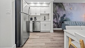 Cozinha moderna com armários brancos, eletrodomésticos de aço inoxidável e piso de madeira.