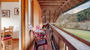 A wooden balcony with a view of a grassy landscape and trees. - 'Elzblick' Apartment with Shared Pool, Garden, and Wi-Fi (Elzach)