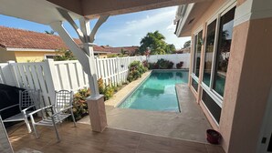 Une terrasse couverte avec une piscine, une clôture blanche et une vue sur les maisons voisines.
