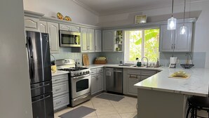 Une cuisine moderne dotée d’appareils électroménagers en acier inoxydable, de meubles blancs et d’un grand îlot central.