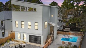 Una casa moderna de dos pisos con garaje visible, piscina y un carrito de golf.
