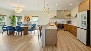 Una cocina moderna con una isla central, armarios de madera e iluminación colgante.