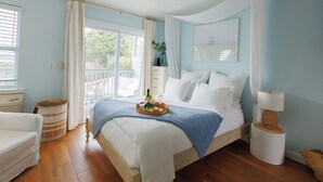 A bedroom with a bed, a bedside table, a lamp, a wicker basket, and a window with curtains. - 30A Gem • Steps to Sand • Balcony Sunsets • Pool (Inlet Beach)